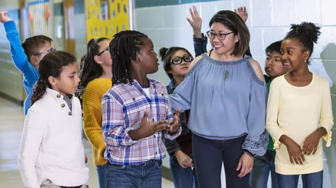 A teacher with their students in a school hallway