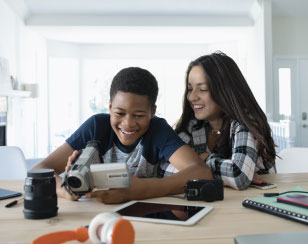 A multiracial pair of students work together with a digital camcorder